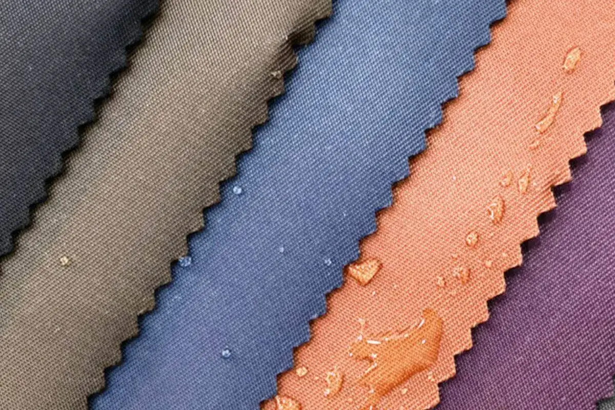 Muestras de tela de poliamida en varios colores, algunas con gotas de agua que demuestran su impermeabilidad.