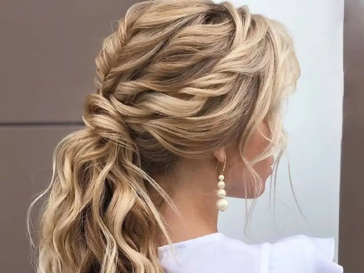 Coleta para invitada boda: melena rubia con trenzas y ondas sueltas, ideal para un evento especial.
