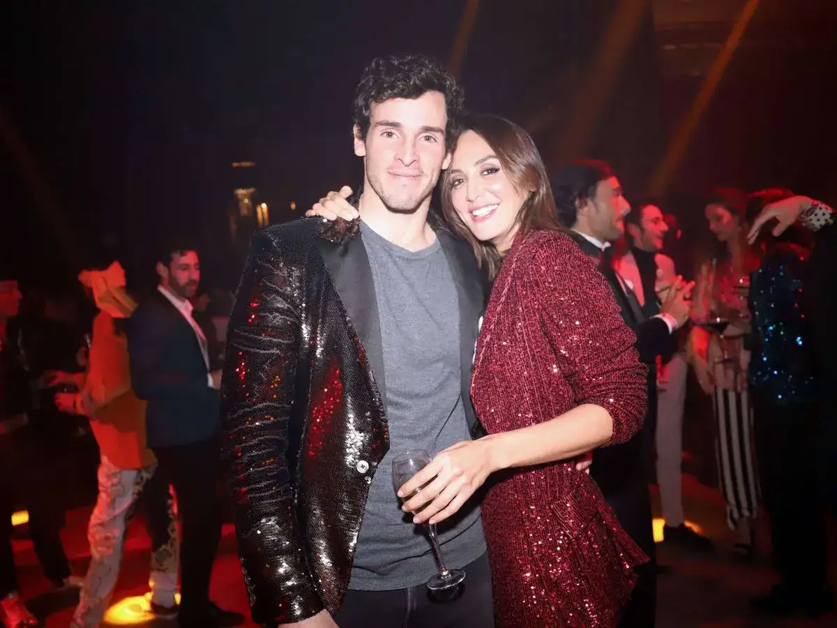 Tamara Falcó e Iñigo Onieva, radiantes en una fiesta, ella con un vestido rojo brillante, él con chaqueta de lentejuelas negras.
