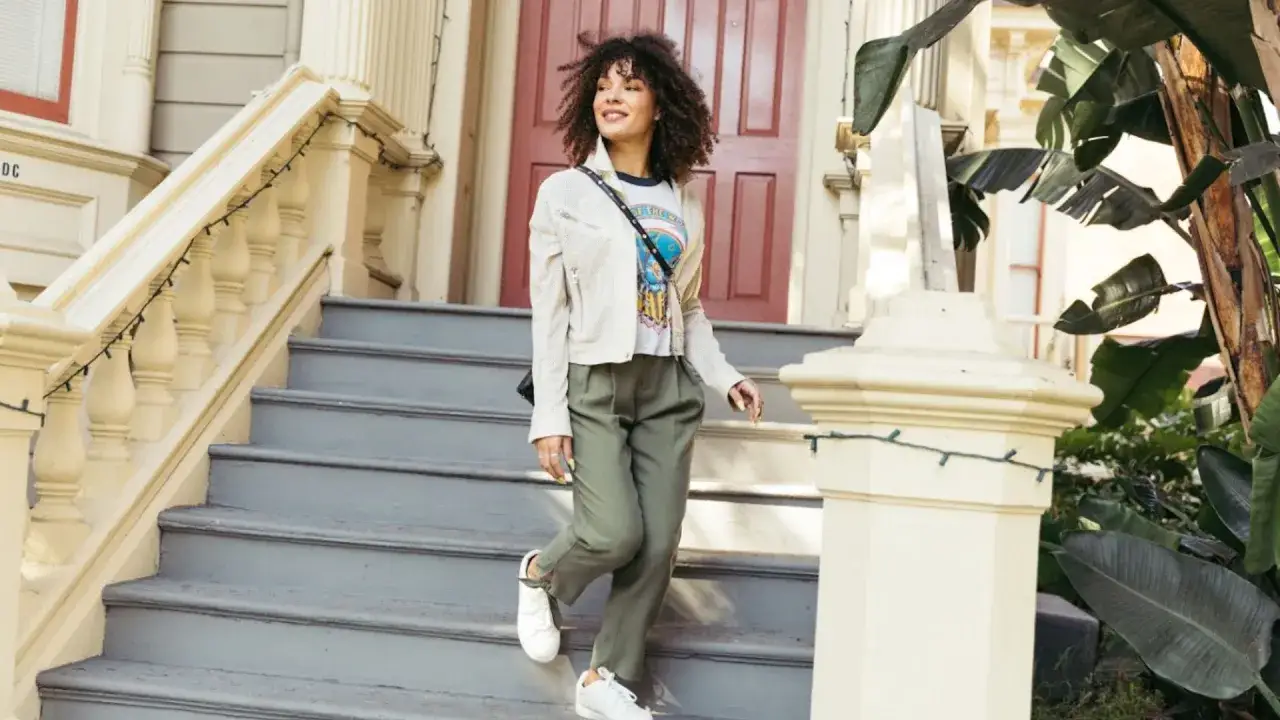 Mujer con pelo rizado baja unas escaleras, vistiendo ropa que se ve muy comfy.