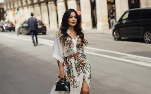 Mujer con vestido estampado floral, estilo manga francesa, pasea por París con un bolso verde.